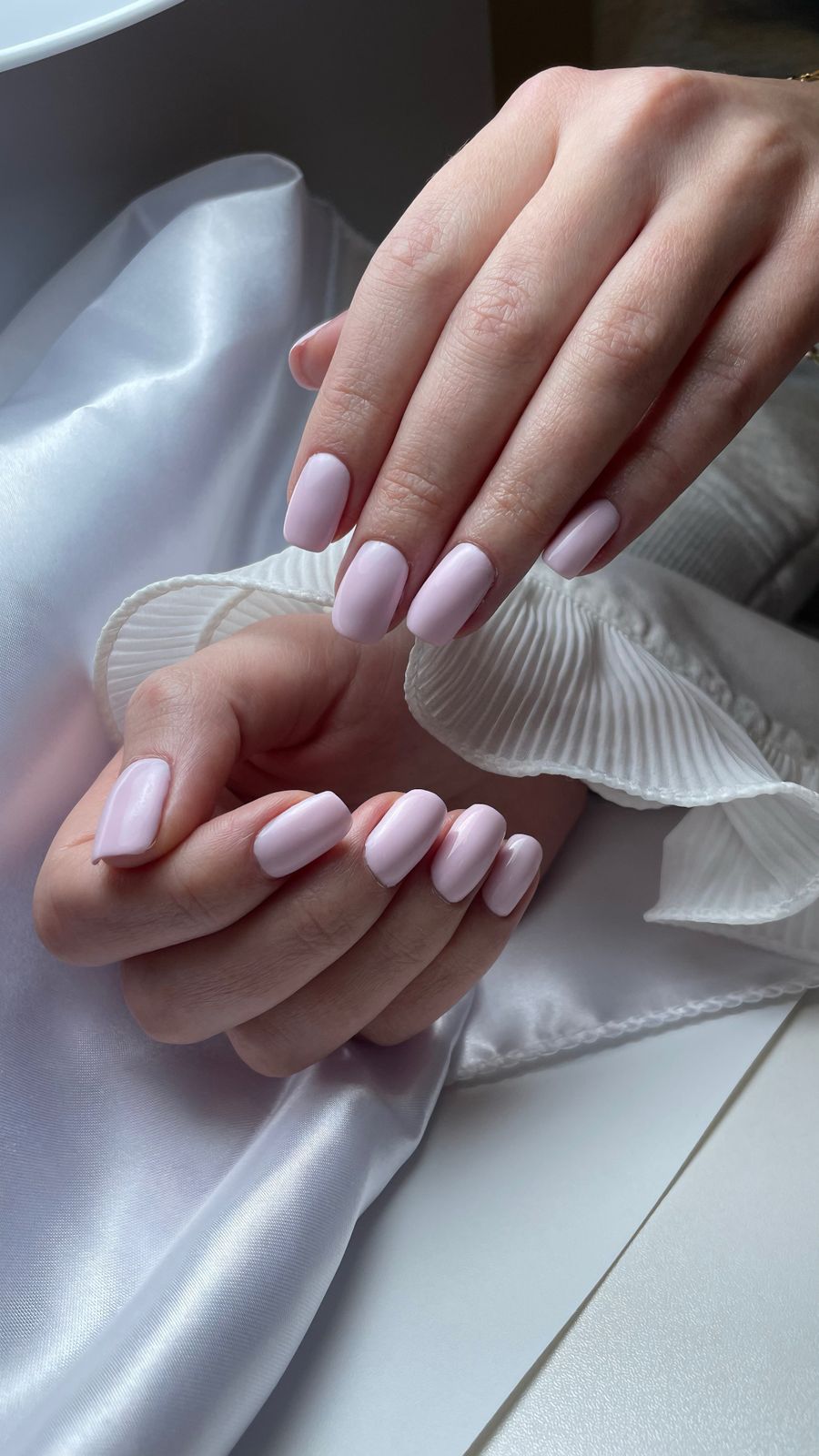 A pale pink manicure against ivory silk, reference photography